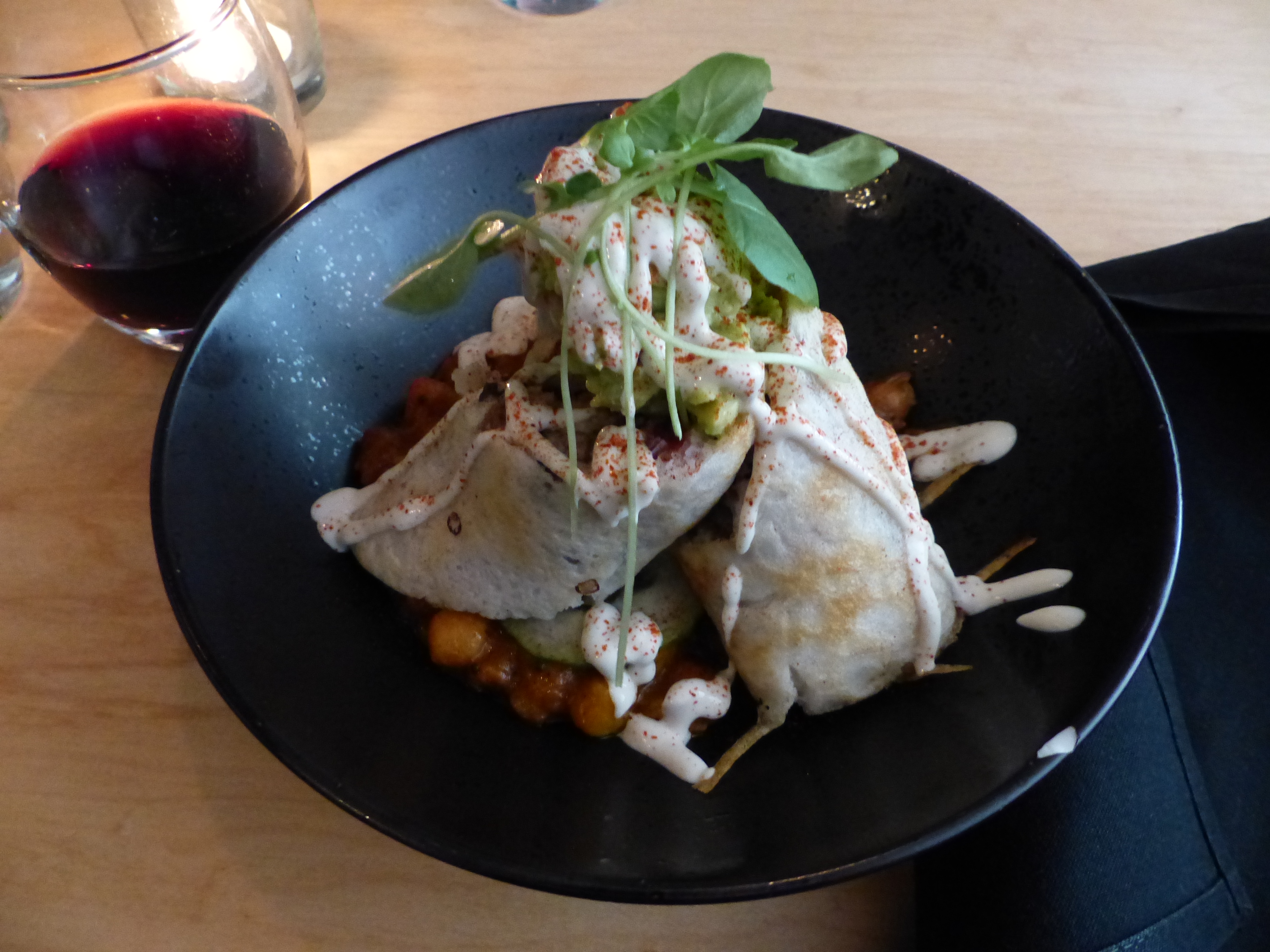A plant-based dish of wraps over chickpea stew with a drizzle of sauce and fresh herbs