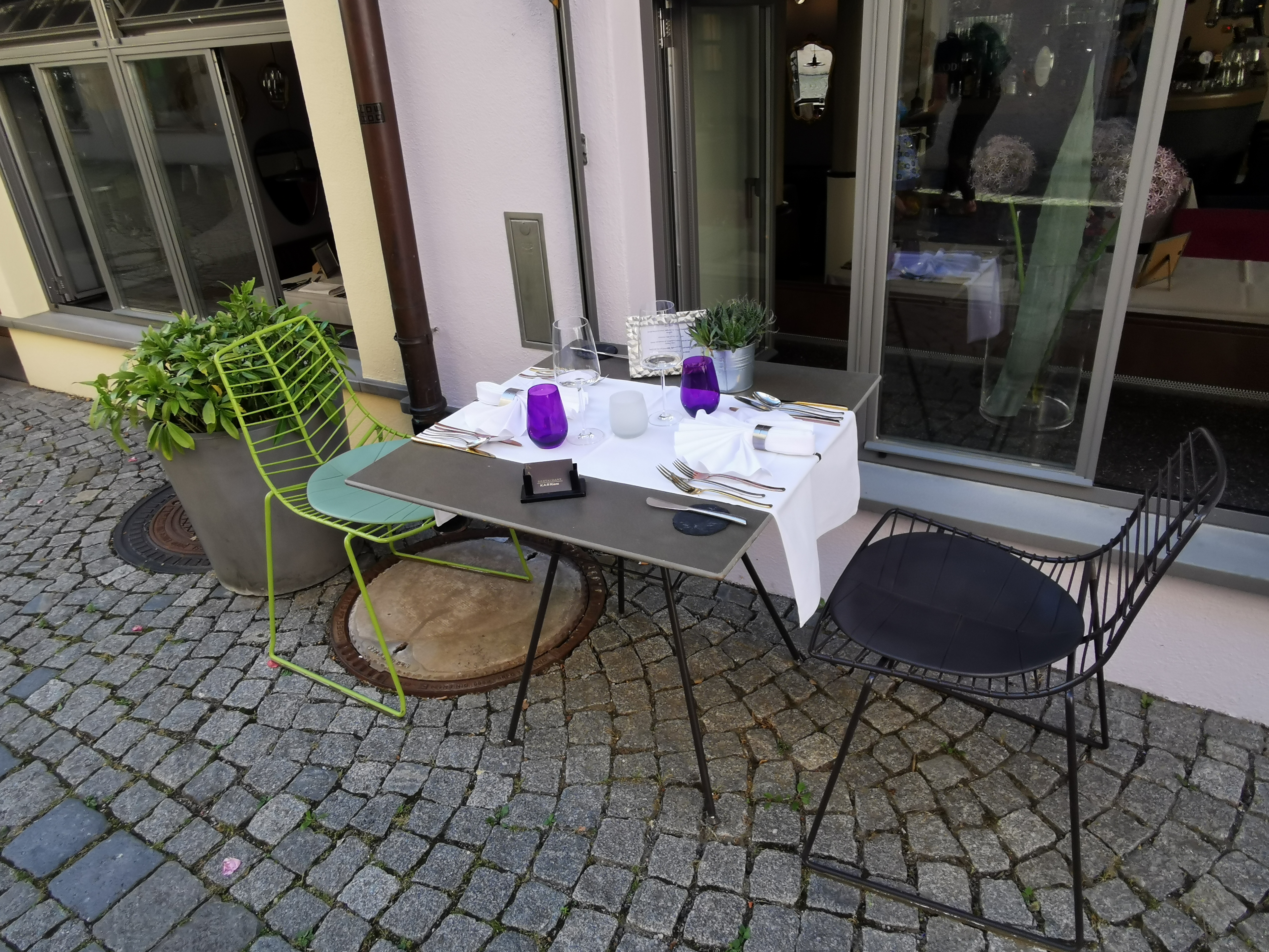 Small outdoor restaurant table laid for two on a cobbled street