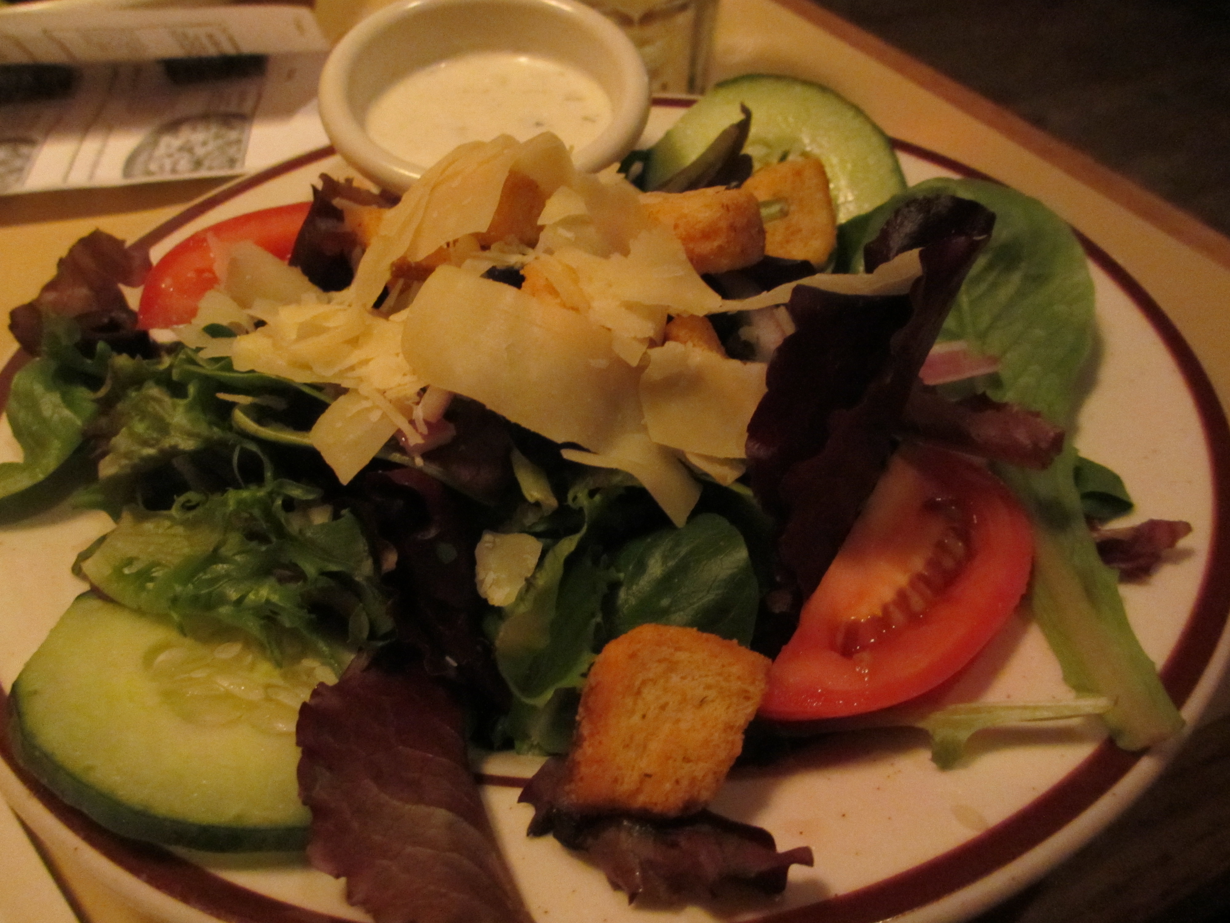 Mixed leaf salad with tomato and cucumber, with the dressing served in a separate small pot
