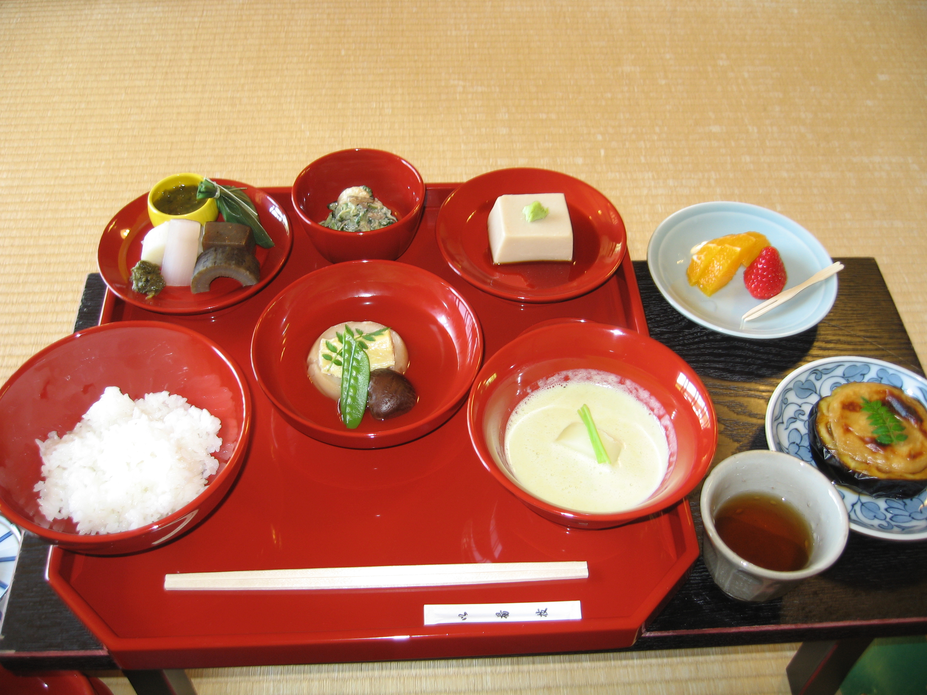 Japanese Buddhist temple meal of rice, tofu, simmered vegetables and soup in red lacquer bowls on a tray