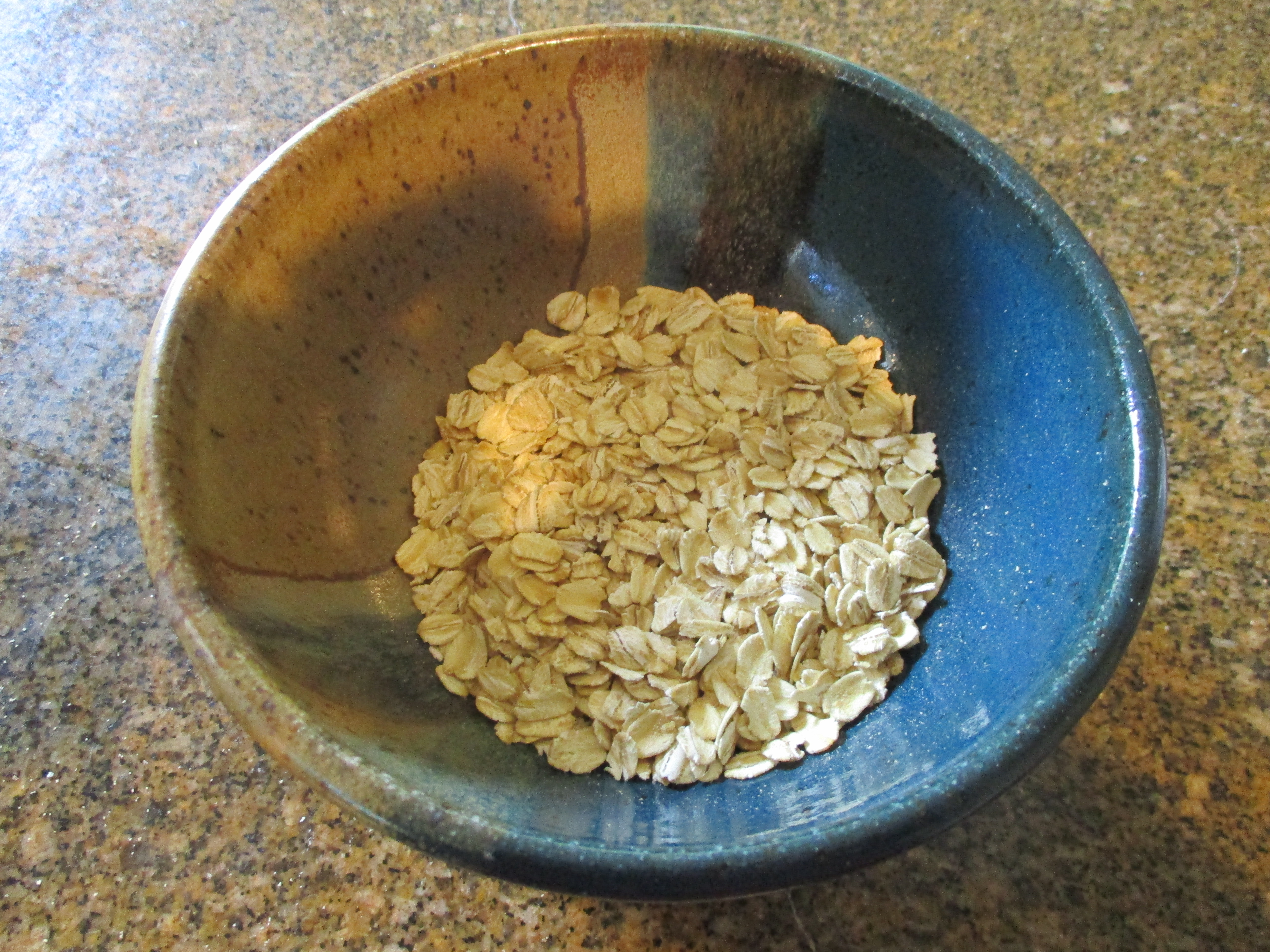 Small blue and brown ceramic bowl holding a portion of rolled oats