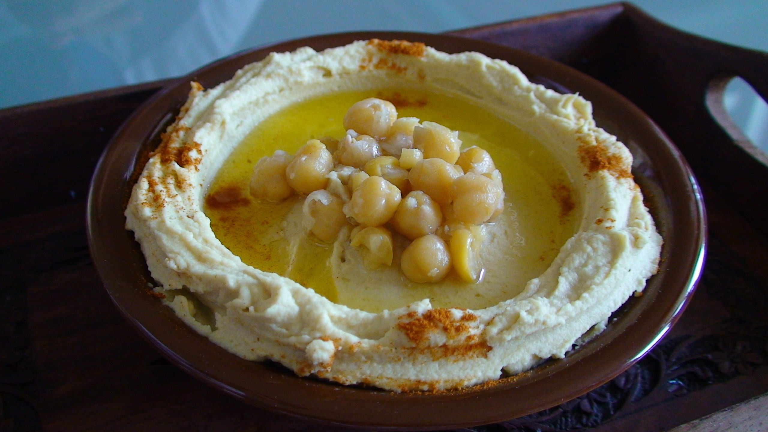 A plate of hummus drizzled with olive oil and topped with whole chickpeas and paprika