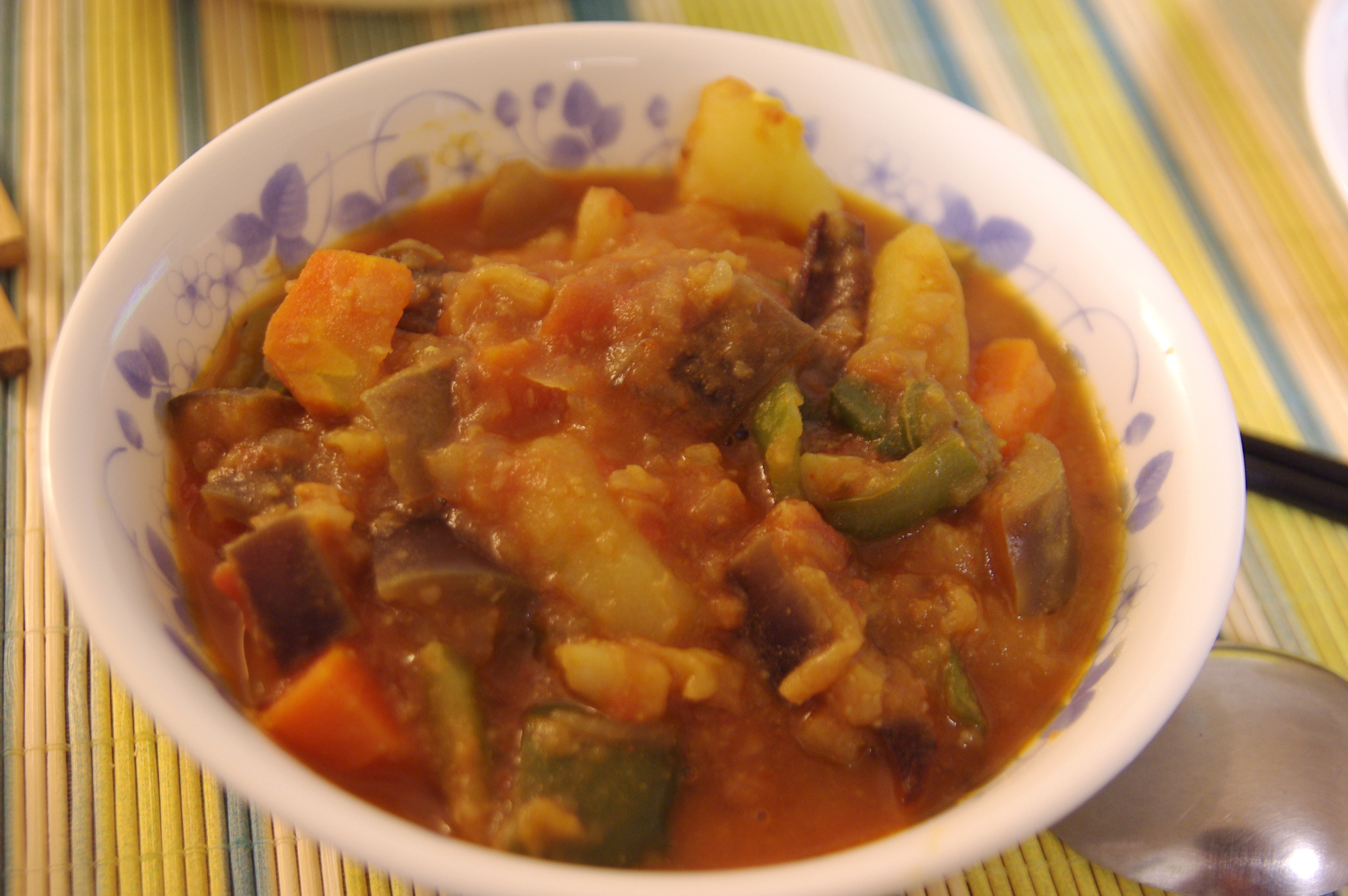 A bowl of chunky vegetable curry with potato, aubergine and peppers